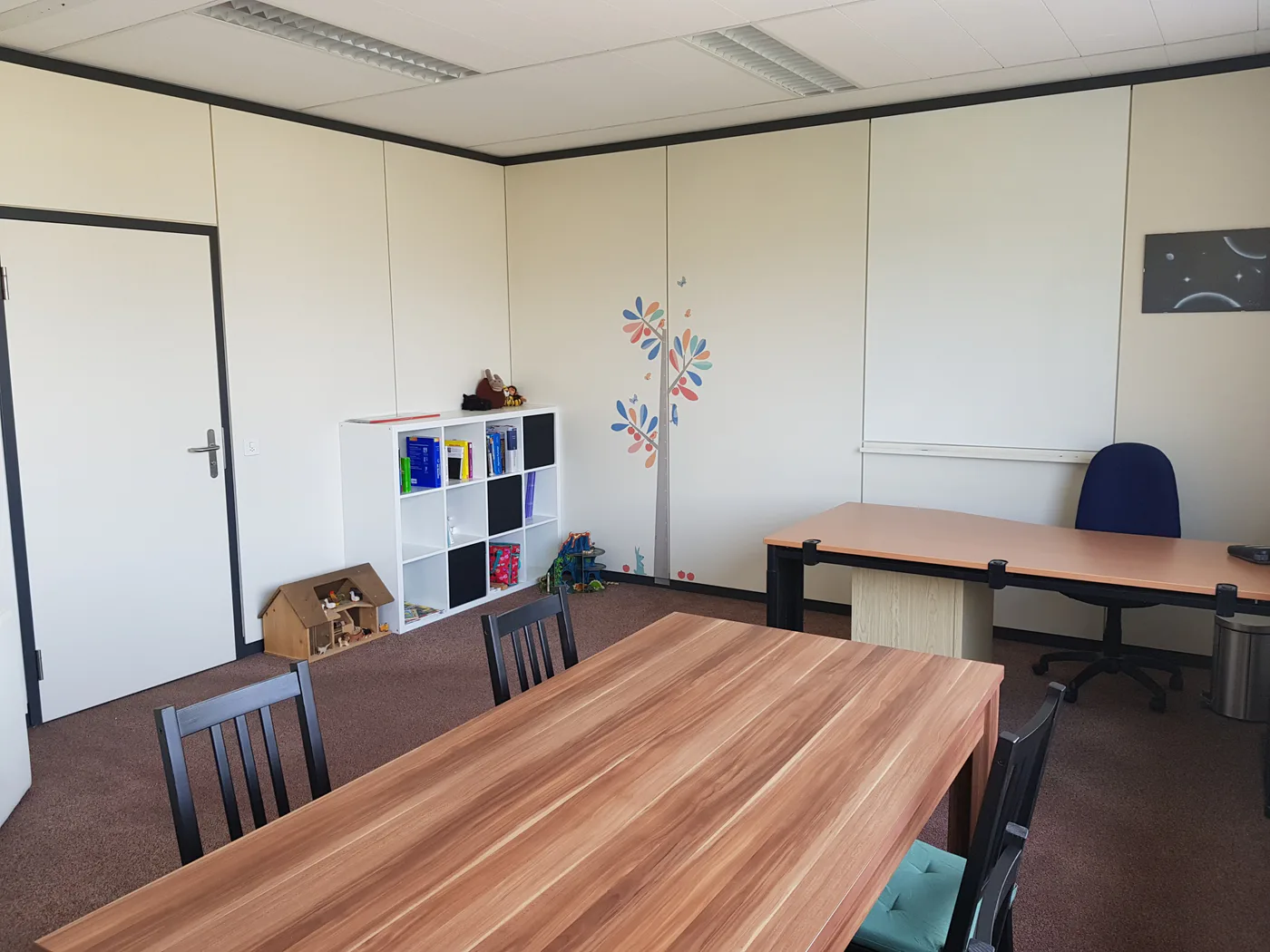 Praxisraum mit Spielbereich und Besprechungstischen